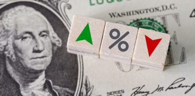 Percentage symbol and arrows on wooden cubes with dollar bill underneath