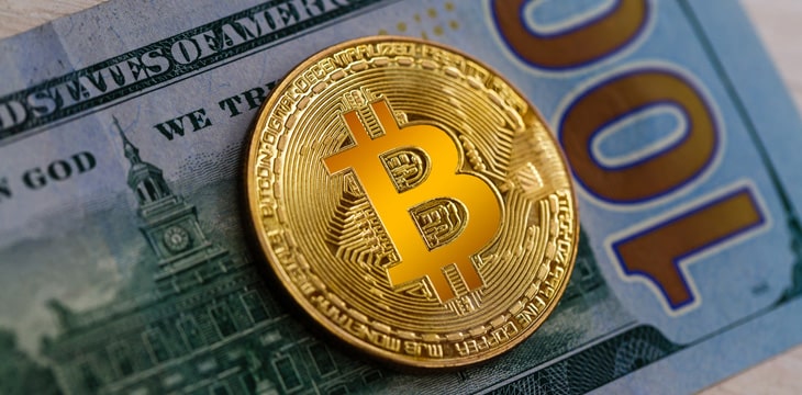 A single gold Bitcoin with a hundred dollar