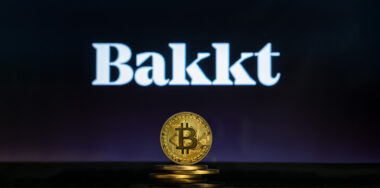 Bakkt logo with stack of gold Bitcoins