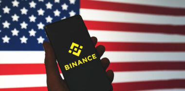 Binance icon on phone with the US flag background