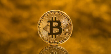 Bitcoin with reflection rendering on a gold backgroun