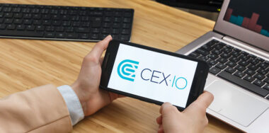 Female trader holding smartphone with CEX IO application running on phone