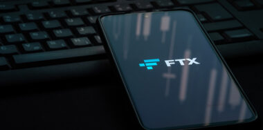 FTX crypto exchange logo on smartphone screen laying on a black computer keyboard