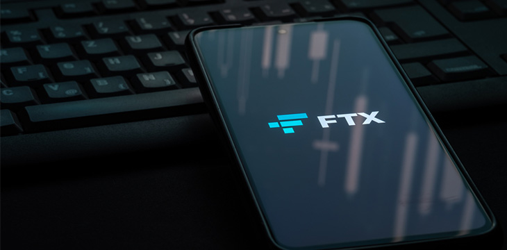 FTX crypto exchange logo on smartphone screen laying on a black computer keyboard