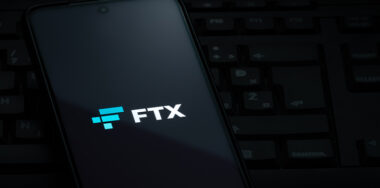 FTX cryptocurrency exchange logo on smartphone screen laying on computer keyboard