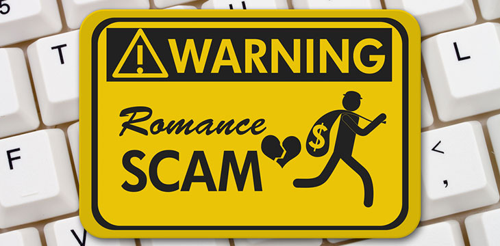 yellow Romance Scam warning sign on a white keyboard