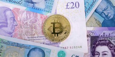 Single virtual cryptocurrency money Bitcoin golden coin on United Kingdom Pound sterling banknotes with faces of Queen Elizabeth II and Winston Churchill.