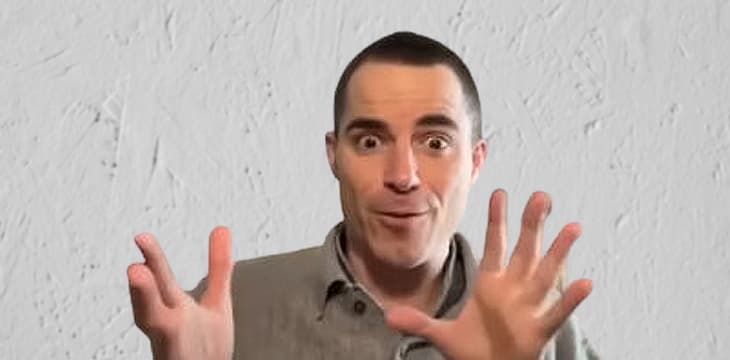 Roger Ver in a surprised expression raising his hands.