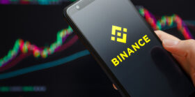 Binance mobile app running at smartphone screen with trading candlestick chart in background