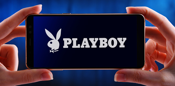 Hands holding smartphone displaying logo of Playboy, an American online men's lifestyle and entertainment magazine