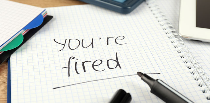 Message You're Fired written on notebook on top of wooden desk