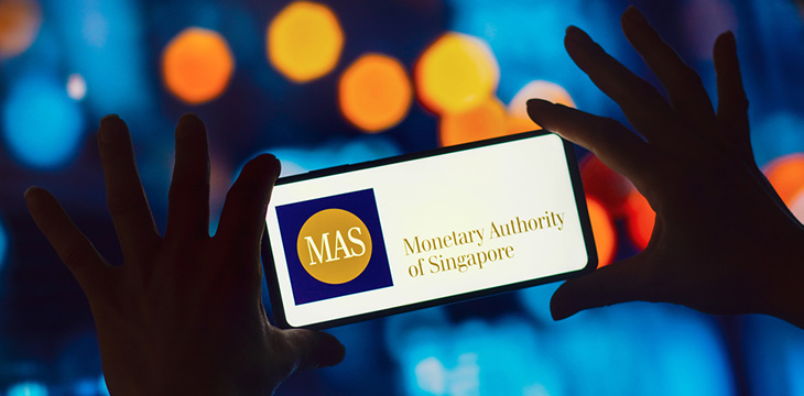 the Monetary Authority of Singapore (MAS) logo is displayed on a smartphone