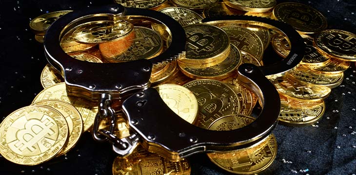 Pile of gold coins with a pair of handcuffs on a black background. — Photo