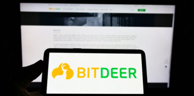BitDeer logo on phone in front of computer screen