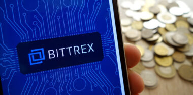 Bittrex app on a mobile phone with stack of coins in the background