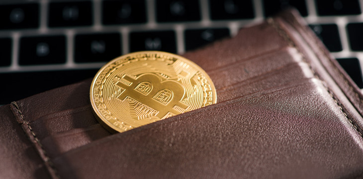Gold bitcoin inside a brown leather wallet