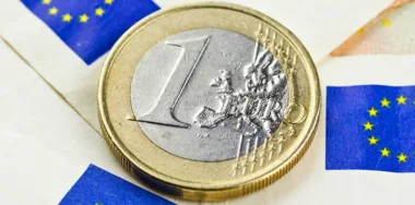 Euro coin with euro flags in the background