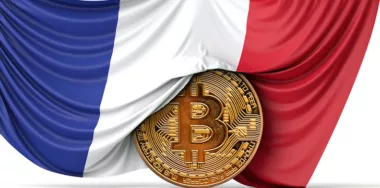 France flag draped over a bitcoin cryptocurrency coin