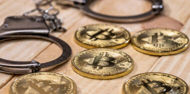 Handcuff and gold bitcoins on top of a table