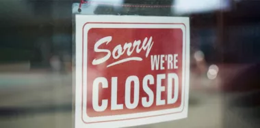 Sorry we're closed sign behind dirty glass door