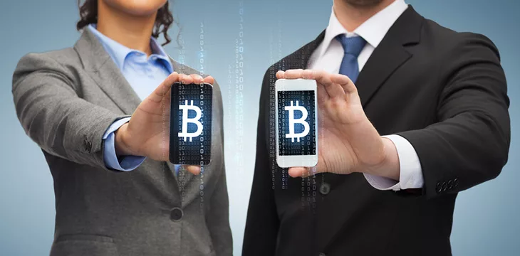 businessman and businesswoman with bitcoin sign on smartphone screens