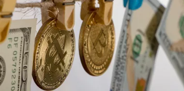 yellow clothes peg holding gold bitcoins and dollar bills