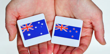 two hands holds the national flags of Australia and New Zealand