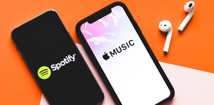 logos of spotify and apple music on phone screen with airpods
