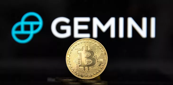Gemini digital currency exchange logo displayed on a screen with Bitcoin in front