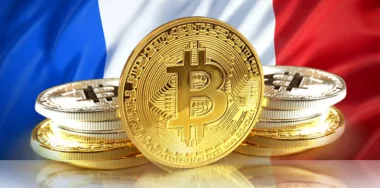 Bitcoin in between stacks of Bitcoins with flag of France in the background