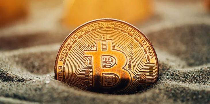 Bitcoin cryptocurrency coins buried in sand