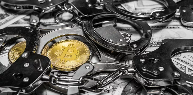 Conceptual photography of financial fraud Bitcoin surrounded with handcuffs