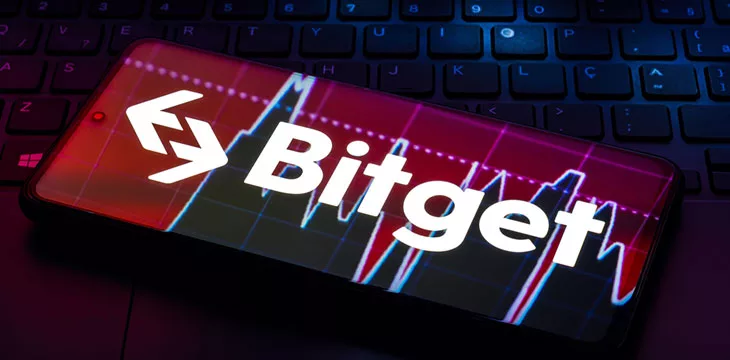 Bitget logo shown on smartphone screen on top of computer keyboard