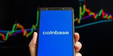 Coinbase mobile app running at smartphone screen with trading candlestick chart at background