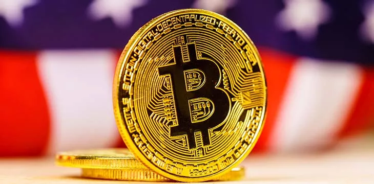 gold bitcoins in front of blurred US flag