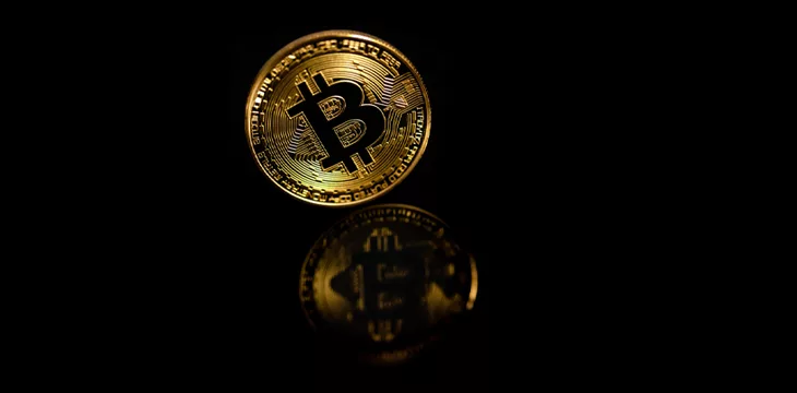 Closeup golden bitcoin with reflection isolated on black background