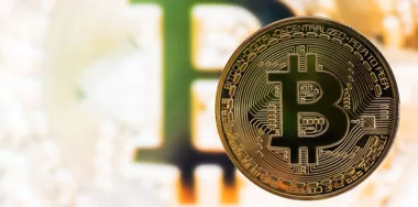 Gold Bitcoin in front of a blurred golden bitcoin background