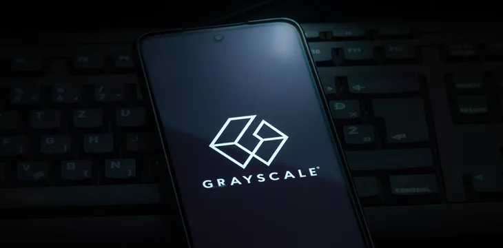 Grayscale investing logo on smartphone screen laying on computer keyboard
