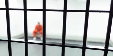 Prisoner behind bars sitting on the floor
