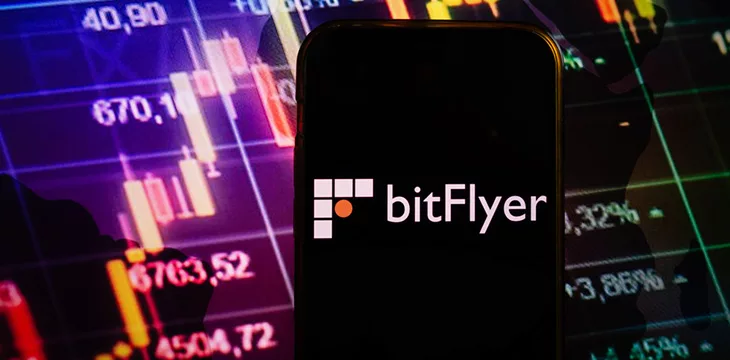Smartphone displaying logo of bitFlyer cryptocurrency exchange on stock exchange diagram background
