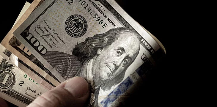 close up of hands holding folded dollar bills