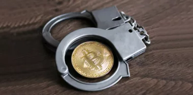handcuffs with gold bitcoin in the middle
