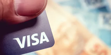 someone holding a visa card in front of blurred money background