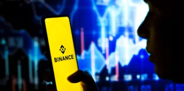 Smartphone displaying Binance logo being held by a person