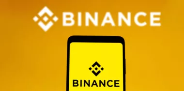 Binance logo is displayed on a smartphone screen and in the background