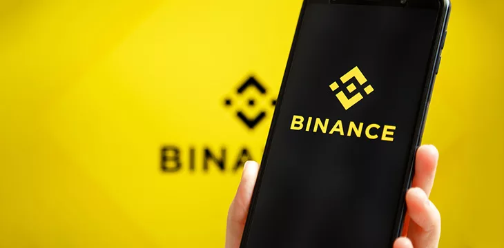 Binance mobile app running at smartphone screen with Binance logo at background. Binance one of the world's leading cryptocurrency exchange and trading platform
