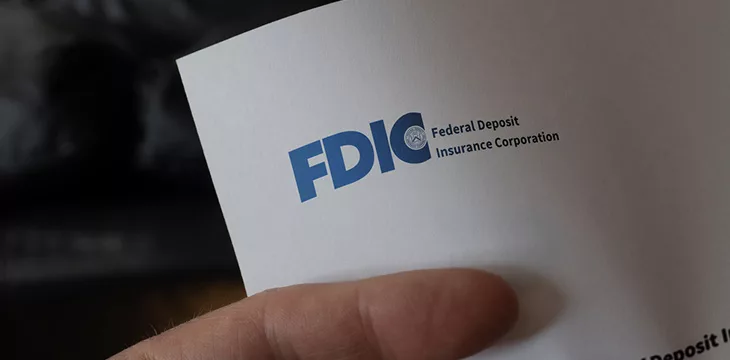 hand holding a paper with FDIC logo