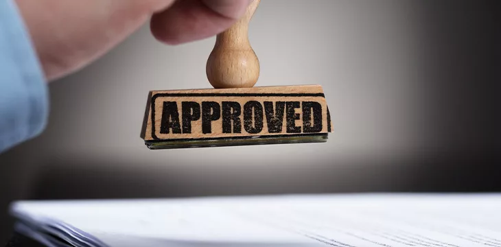 Close-up Of A Businessperson's Hand Stamping On Approved Contract Form