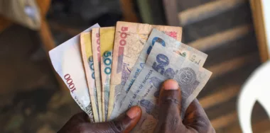 Hands holding spread of multiple Nigerian naira notes, cash, currency in an outdoor setting