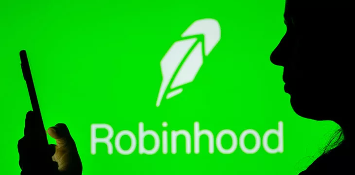 a person using a cellphone in front of robinhood logo